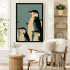 Retro emperor penguin family framed poster beside a Scandinavian armchair, vintage-style black cream and teal blue penguin wall art for reading nook or study