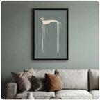 Black framed abstract dog wall art print showing a stylised greyhound silhouette in cream on a dusty blue-green background, mounted above a neutral linen sofa against a sage green wall