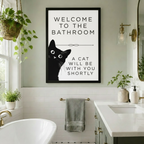 Black cat peeking humorous bathroom quote framed print mounted on sage green wall between a freestanding bathtub and double vanity with brass fixtures and hanging plants