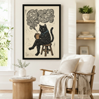 Framed vintage-style black cat coffee art print with swirling steam design hung beside a white armchair in a Scandinavian-inspired reading corner