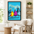 Black framed colorful funny birds squad canvas art showing four quirky wide-eyed cartoon birds — two in slate blue flanking a yellow-orange and a magenta bird — painted in loose expressive strokes on a bright sky blue background, displayed beside a white armchair in a cozy reading nook