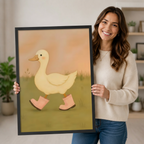 Smiling woman holding a large framed wall art print of a cute white duck wearing pink rain boots, showcasing print size, black frame detail, and warm peach tones for nursery or living room decor