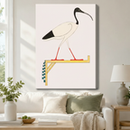 Gallery-wrapped canvas of an ancient Egyptian sacred ibis bird on a gold and checkered perch with cream background hung above a white sofa in a cozy neutral living room