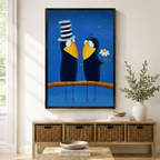 Black framed whimsical folk art romantic crow couple canvas art with two plump dark navy blue cartoon crows perched side by side on a warm amber branch facing each other lovingly, the left crow wearing a tall black and white striped stovepipe top hat and the right crow holding a white daisy flower, both with wide golden yellow beaks and white eye rings on a rich royal blue starry night background with scattered gold dot sparkles, displayed above a light wood rattan basket storage console with