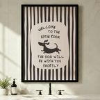 Black framed funny bathroom dachshund stripe canvas art with bold black and white vertical stripes and a central oval featuring hand-lettered welcome to the bathroom above a running cartoon dachshund silhouette and the quote the dog will be with you shortly in a minimalist black and white bathroom above a sink with a black faucet and soap dispenser
