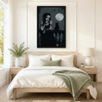 Striking framed dark gothic wall art of a tattooed woman and black cat silhouetted against a dripping full moon on a night balcony, displayed above a white and sage linen bed in a serene Scandinavian bedroom