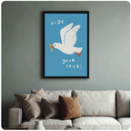 Quirky seagull wall art in black frame hung above cream linen sofa, bold blue illustrated print with playful hand-lettered text