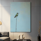 Gallery wrap stretched canvas of a green hummingbird resting on a single slender bare branch with generous negative space on a dusty blue background hung frameless on a gray wall above a dark sofa and candlesticks