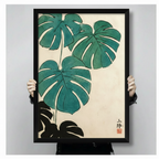 Japanese brush painting monstera canvas art in a black frame held up against a light gray background, showing teal leaves and ink seal detail