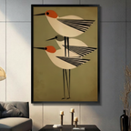 Framed mid-century modern bird trio canvas wall art with three geometric shorebirds in orange and black striped wing design on olive green background in a modern living room