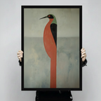 Person holding a large black framed abstract heron bird canvas print with bold terracotta body against light gray background