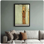 Framed wall art print of a curious golden dog peeking through a wooden door gap, displayed above a grey linen sofa in a modern living room