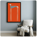 Framed retro-style wall art print featuring a tall minimalist greyhound in a striped top on an orange background, hung beside a cozy white armchair in a Scandinavian-style room