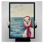 Hand-held display of a black-framed canvas art print featuring a close-up oil painting of a seagull in a red headscarf and scarf against a shimmering blue ocean — coastal bird wall art