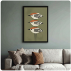 Framed mid-century modern bird art print hung above a cream sofa in a blue-grey living room, featuring three stacked geometric birds