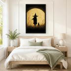 Black framed vintage folk art little witch and black cat under a full moon canvas art with a long-haired witch in a pointed hat beside a black cat gazing at a giant golden moon with bats in a grainy sepia sky, hung above a wooden bed frame in a sun-drenched bedroom with crisp white linen bedding, a sage green throw,