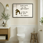 Welcome to the bathroom a dog will be with you shortly humorous line art in black frame above toilet in warm beige bathroom with wainscoting – gold mirror brass sconce wood vanity brown cartoon dog cream background funny dog toilet wall art