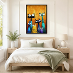 Black framed whimsical colorful cat family canvas art with five expressive cats in black teal cobalt blue golden yellow and purple with wide cartoon eyes and dramatic whiskers in thick impasto oil-paint style on a glowing amber floral-textured background, hung above a light wood bed with white linen bedding and a sage green throw in a serene Scandinavian bedroom