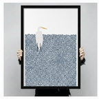 Person holding a large black framed minimalist white egret in pointillist navy blue water art print showing print size scale and fine dot texture detail