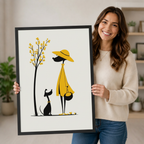 Smiling woman in cream sweater holding a large black framed minimalist yellow dress girl and black dog illustration print in a bright home interior