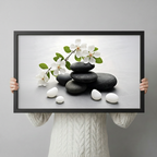 Person holding a black framed zen stones and cherry blossom canvas art print against a light gray backdrop showcasing print size and frame detail